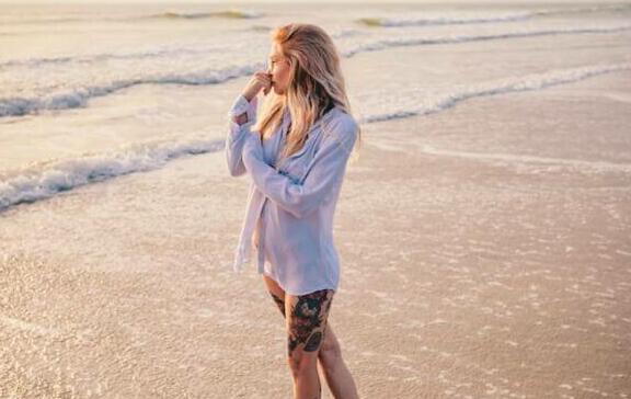 A woman standing on top of a beach next to the ocean