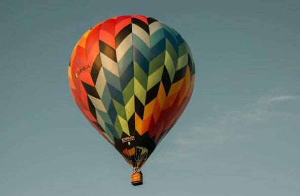 Hot air balloons soar through the clear sky.