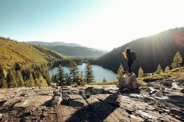 Woman and dog enjoy a scenic mountain lake view.