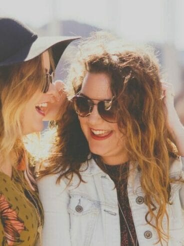 two women smiling while wearing sunglasses
