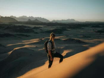 a woman standing on top of a sand dune